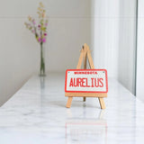 Personalized mini license plate displayed on wooden tripod stand for product presentation