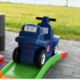 Blue toy car on a green ramp with grass in the background. Personalized Mini License Plate Tag – Custom 4x2” State Plate for Kids, Car Toy, Wagon, Bike, Stroller – Thick Plastic Name Sign.