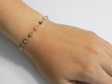 Multicolor evil eye bracelet held in a hand to show scale and detail of the tiny nazar charms.